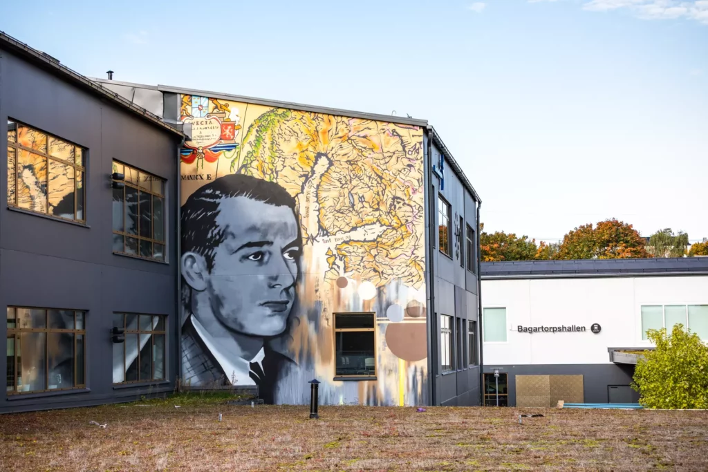 Muralmålning på Bagartorpskolan där en karta på Norden syns i färg bakom Raoul Wallenberg som är avbildad i svartvitt till vänster på byggnaden.