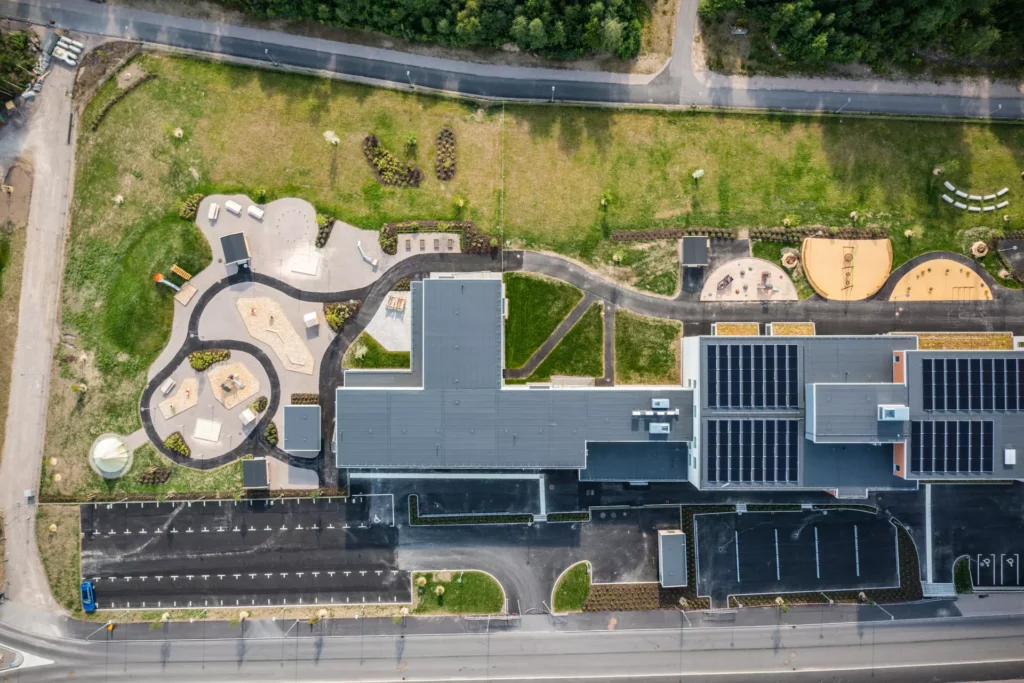 Flygbild tagen ragt ovanifrån och visar skol- och förskolegård samt solcellerna på skolans tak.