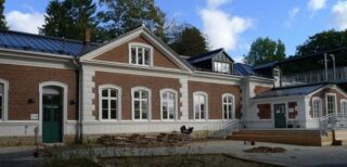 En äldre tegelbyggnad med stora, välvda fönster.
