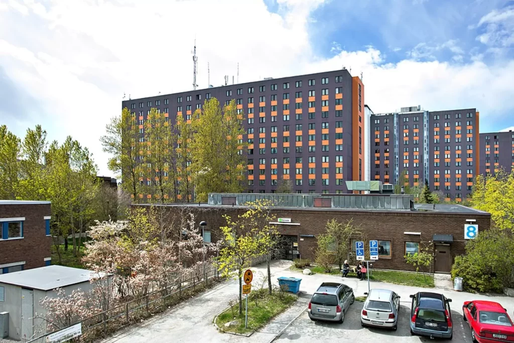 Tre höga hus står på rad. alla husen har många små fönster.