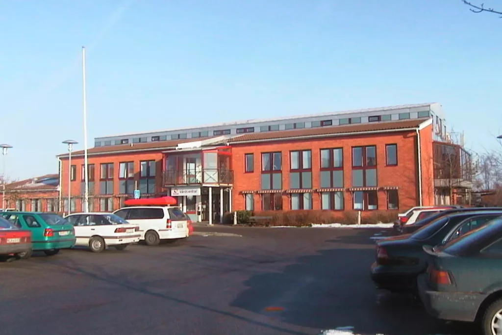 Tvåvåningsbyggnad i tegel med parkering framför
