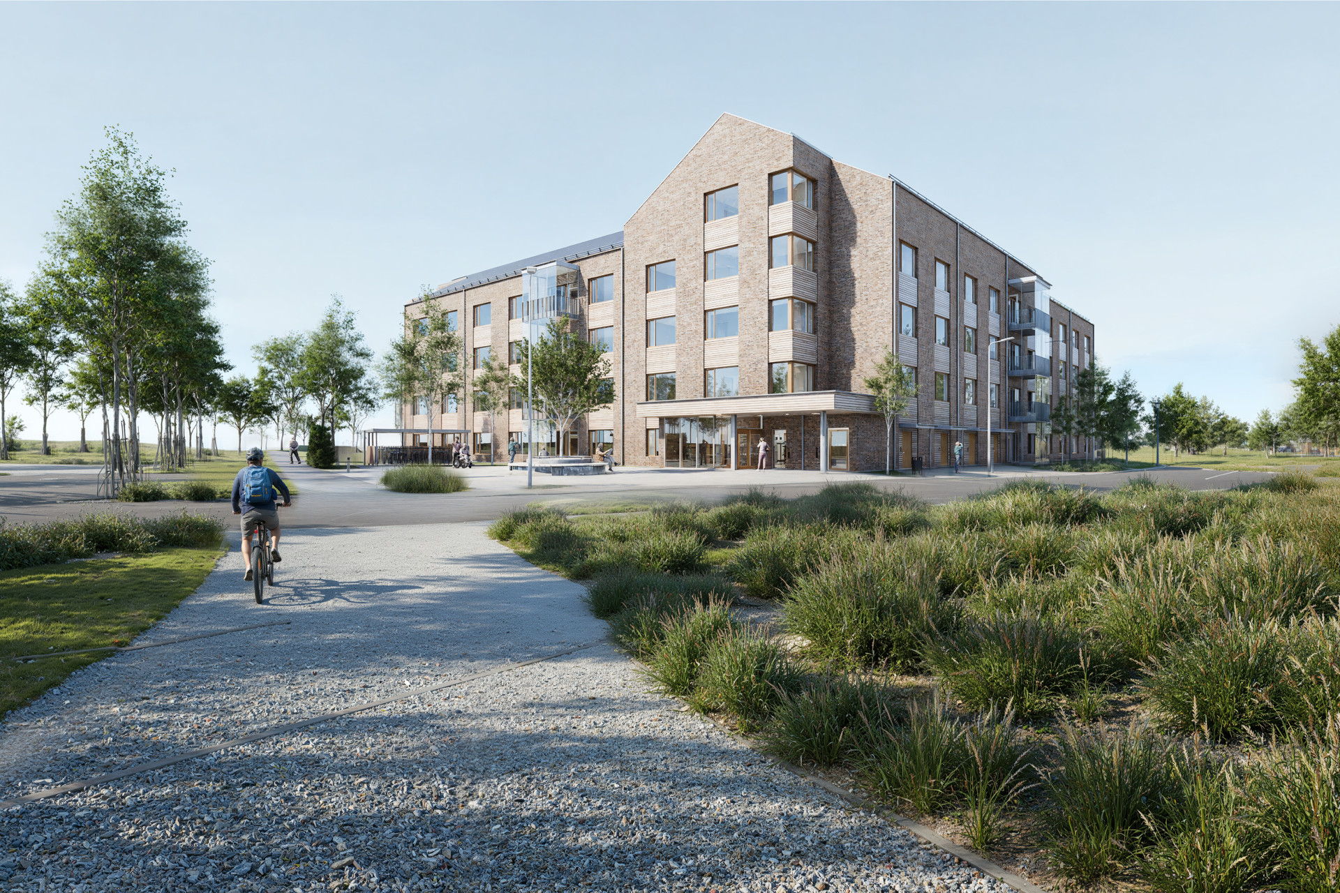 En man cyklar på en grusväg bredvid en hög byggnad.