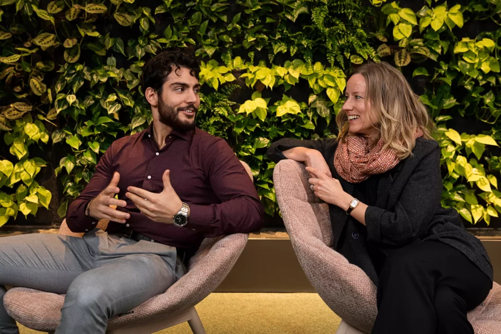 Two coworkers interacting with eaxh other in a lounge at the office.