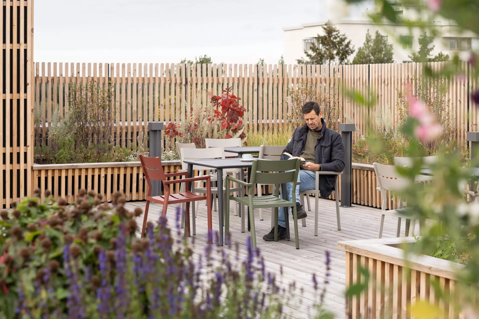 Ein Mann macht eine Pause auf der Dachterrasse eines der Altenheime von Hemsö, umgeben von Pflanzen und bunten Blumen.